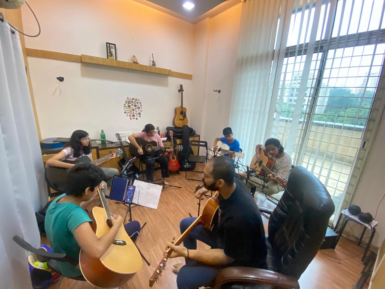Students learning guitar together with an instructor at Revolution Music