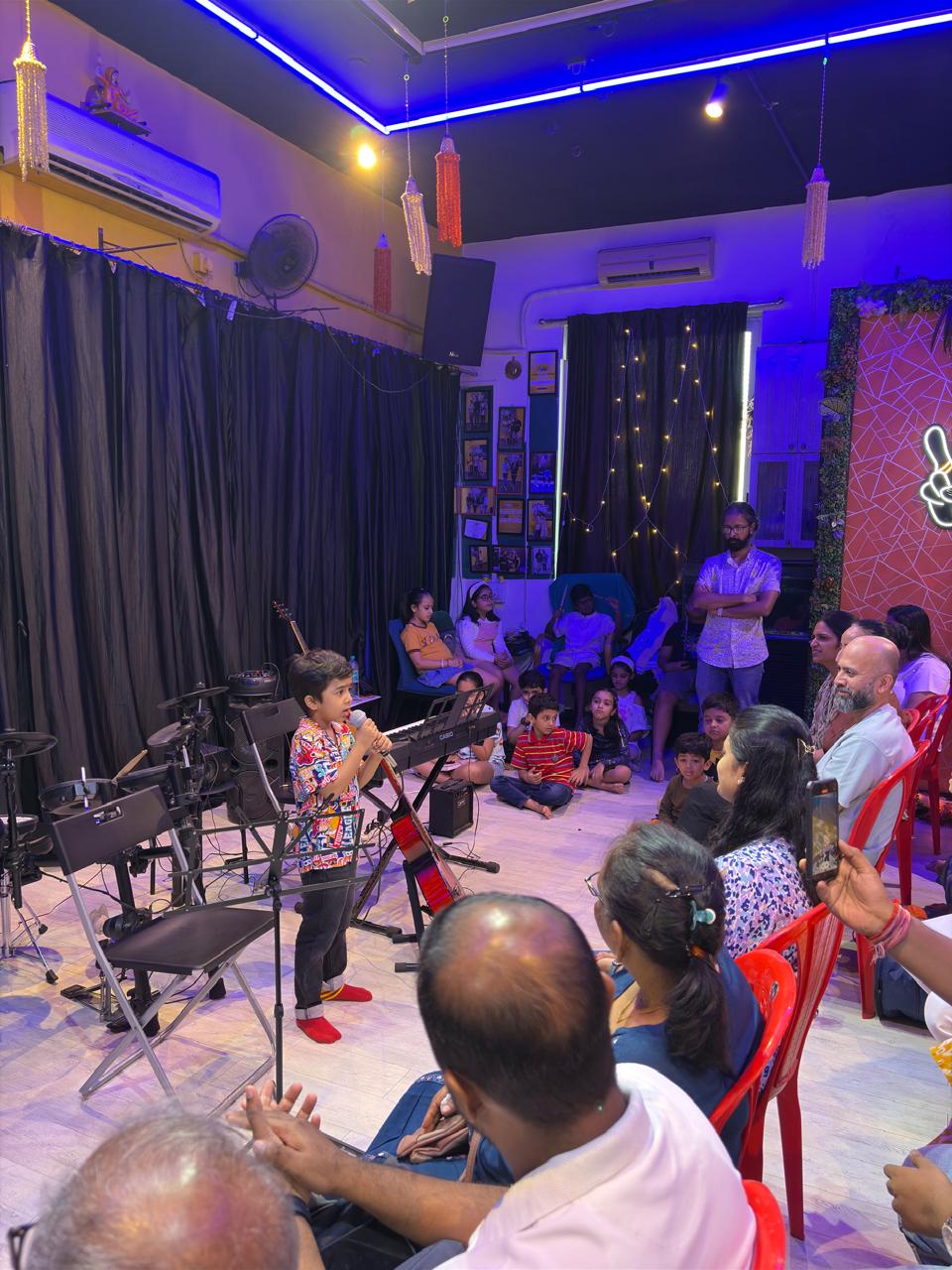 A young student singing into a microphone for an audience in the studio
